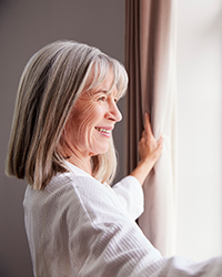 a middle-age woman looking outside of the window