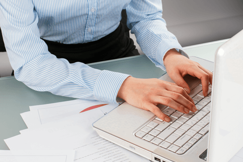 Person at desk typing on a computer