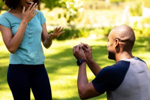 Man proposes to his happy and surprised girlfriend in a field