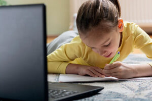 young girl doing homework with laptop